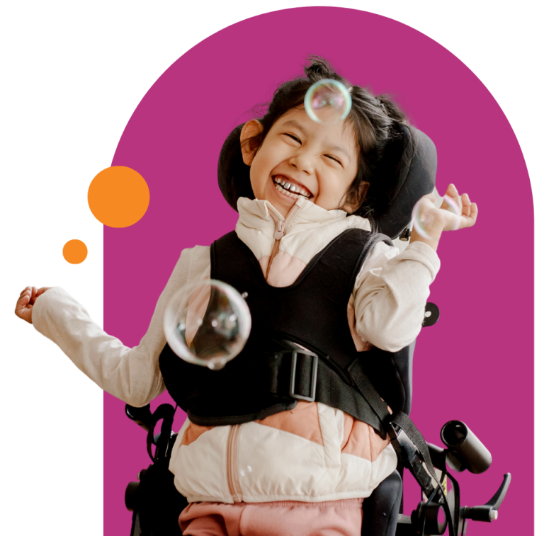 A photo of a young person in a wheelchair smiling with bubbles around them. They're over a deep pink background with orange circles.